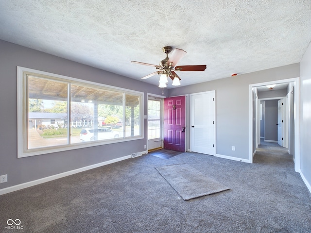 carpeted foyer entrance with ceiling fan, a textured ceiling, and a wealth of natural light