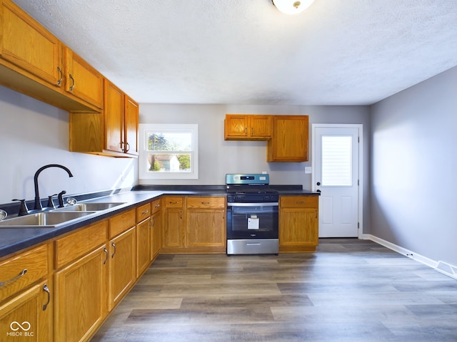 kitchen with a textured ceiling, stainless steel range oven, sink, and dark hardwood / wood-style flooring