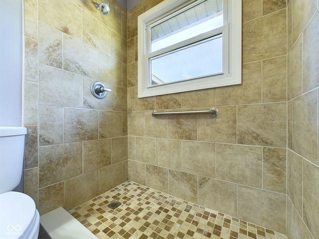 bathroom featuring tiled shower and toilet