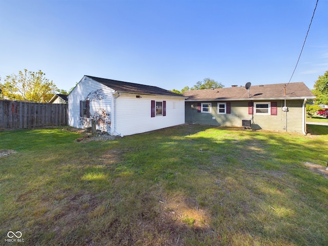 back of house with central AC unit and a yard