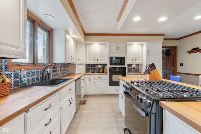 kitchen featuring crown molding, a sink, wooden counters, black appliances, and white cabinets