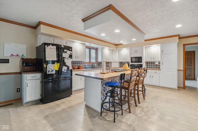 kitchen with white cabinets, backsplash, black appliances, a kitchen breakfast bar, and a center island