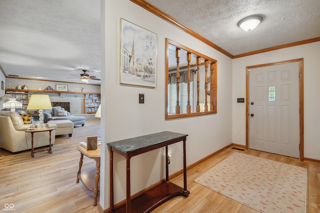 entrance foyer with light hardwood / wood-style floors, brick wall, a brick fireplace, a textured ceiling, and ceiling fan