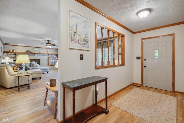 entrance foyer featuring a ceiling fan, ornamental molding, light wood-type flooring, baseboards, and a textured ceiling
