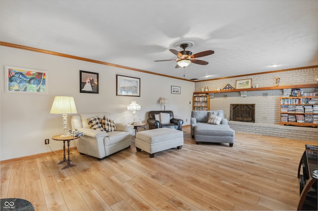 living room with a fireplace, light hardwood / wood-style flooring, crown molding, ceiling fan, and brick wall