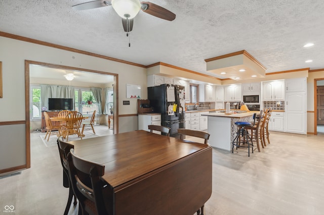 dining area with ceiling fan, crown molding, and a textured ceiling