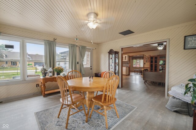 dining room with wooden walls, wood finished floors, and ceiling fan
