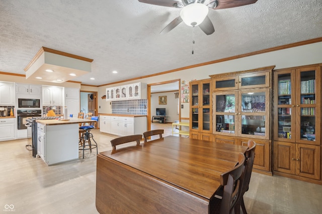 dining room with a ceiling fan, ornamental molding, and a textured ceiling