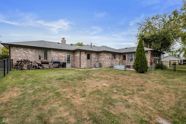 back of property featuring a fenced backyard, brick siding, a chimney, and a lawn