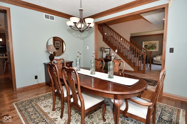 dining room with ornamental molding, a notable chandelier, and hardwood / wood-style floors