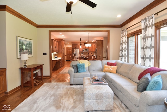 living room with ornamental molding, light hardwood / wood-style floors, and ceiling fan