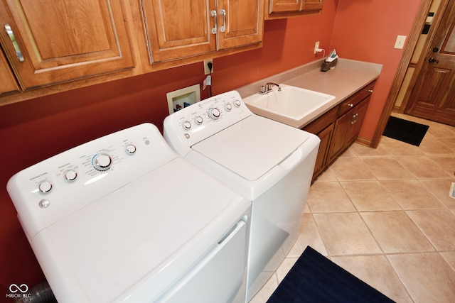 clothes washing area with washing machine and clothes dryer, cabinets, light tile patterned floors, and sink