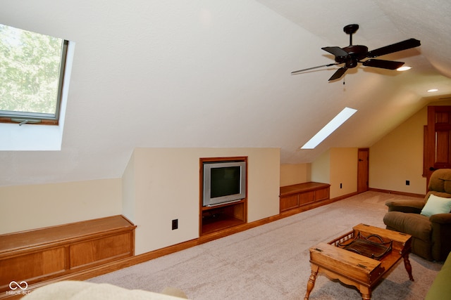 living room featuring vaulted ceiling with skylight, ceiling fan, and light carpet