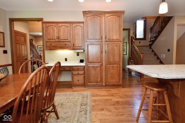 kitchen featuring built in desk, hanging light fixtures, and light hardwood / wood-style flooring