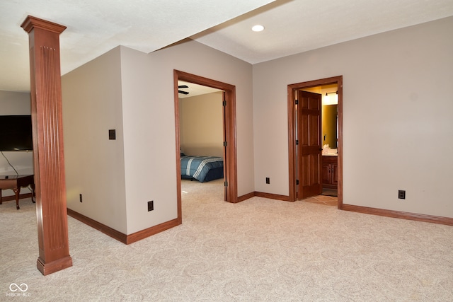 unfurnished bedroom with decorative columns, light carpet, and ensuite bathroom