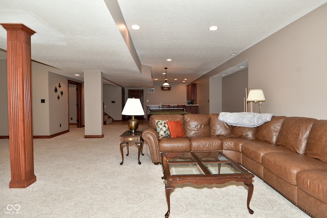 carpeted living room featuring decorative columns and a textured ceiling