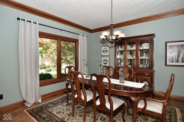 dining area with wood-type flooring, ornamental molding, and an inviting chandelier