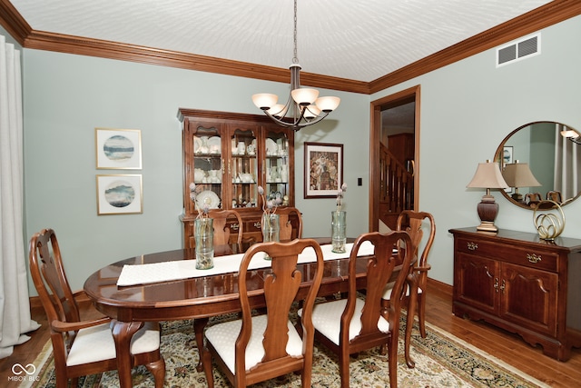 dining room featuring crown molding, an inviting chandelier, and hardwood / wood-style flooring