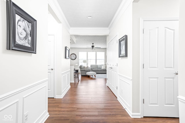 corridor with a textured ceiling, ornamental molding, and dark wood-type flooring