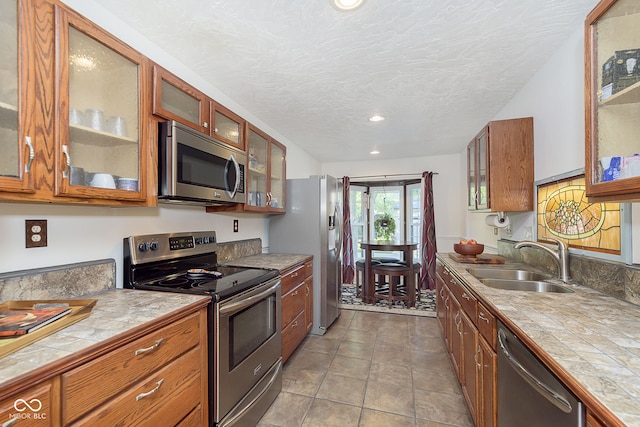 kitchen featuring light tile patterned flooring, sink, a textured ceiling, appliances with stainless steel finishes, and tile countertops