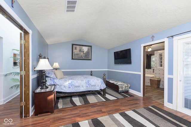 bedroom featuring connected bathroom, lofted ceiling, a textured ceiling, and dark wood-type flooring