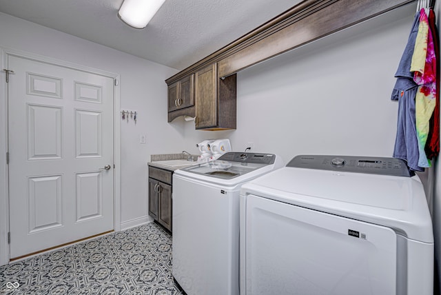 clothes washing area with washer and dryer, a textured ceiling, cabinets, and sink