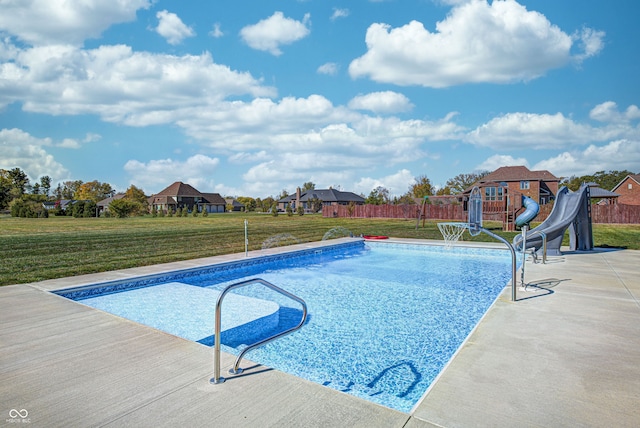 view of swimming pool with a yard and a water slide