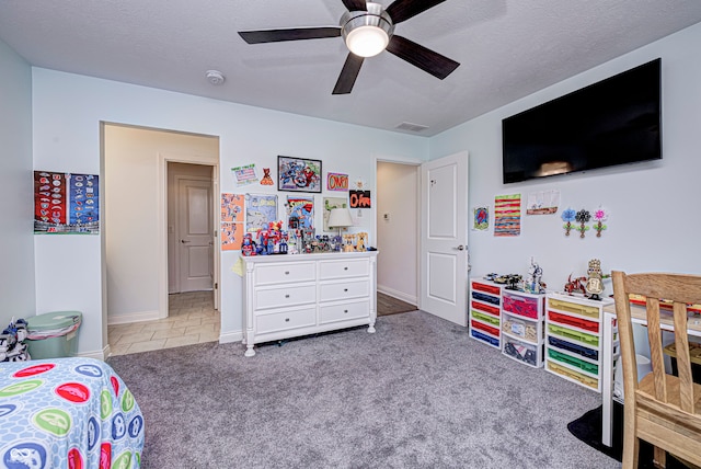 bedroom with ceiling fan, light colored carpet, and a textured ceiling