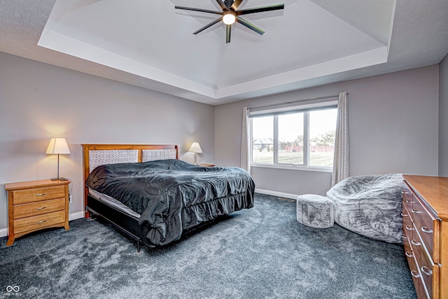 bedroom featuring a tray ceiling, ceiling fan, and dark carpet