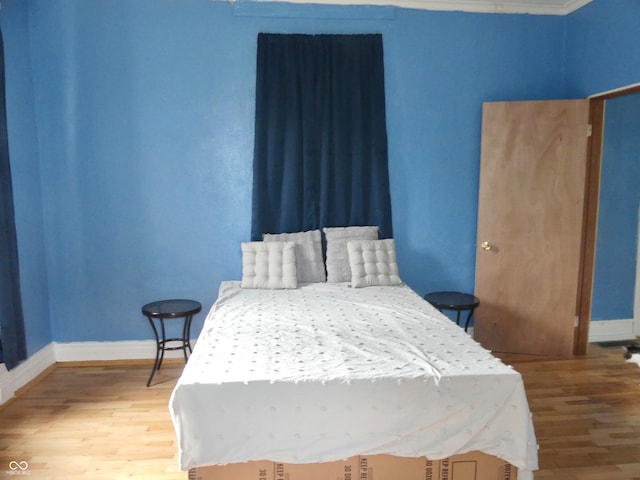 bedroom featuring ornamental molding and hardwood / wood-style floors