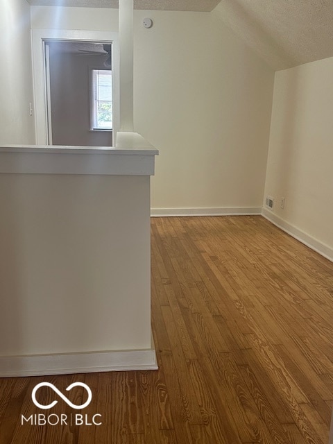 bonus room featuring a textured ceiling, vaulted ceiling, and hardwood / wood-style floors