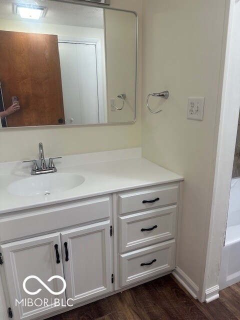 bathroom featuring wood-type flooring, a washtub, and vanity