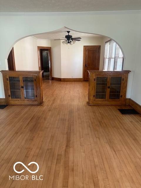 empty room with crown molding, ceiling fan, and light hardwood / wood-style flooring