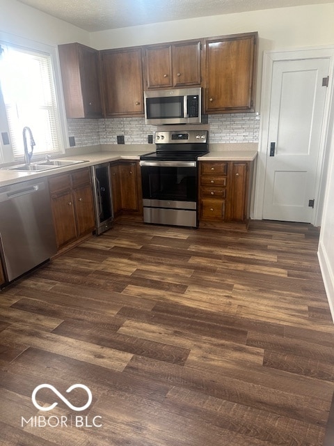 kitchen featuring dark hardwood / wood-style flooring, stainless steel appliances, backsplash, and sink