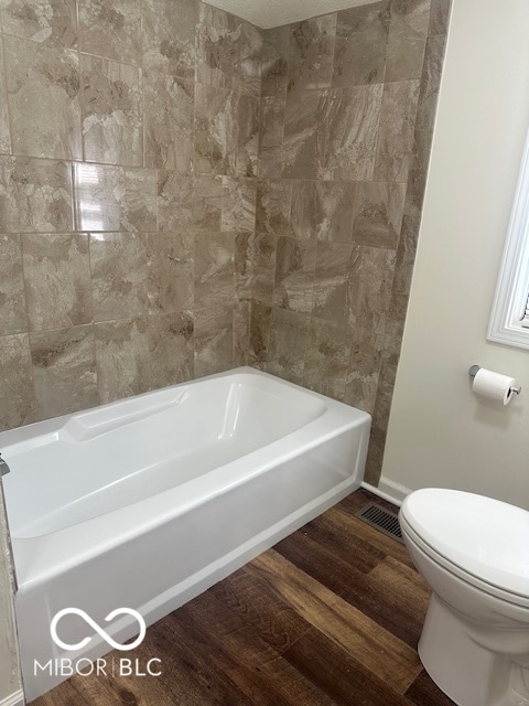 bathroom featuring wood-type flooring, a bathing tub, and toilet