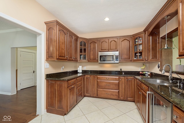 kitchen featuring light tile patterned floors, sink, beverage cooler, decorative light fixtures, and dark stone countertops