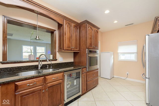 kitchen featuring wine cooler, light tile patterned floors, sink, appliances with stainless steel finishes, and dark stone counters