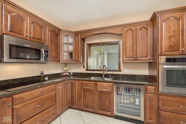 kitchen with light tile patterned floors, sink, beverage cooler, stainless steel appliances, and dark stone countertops