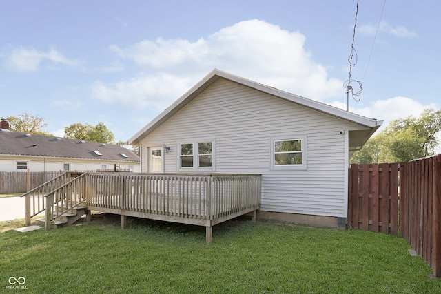 back of property with a wooden deck and a lawn