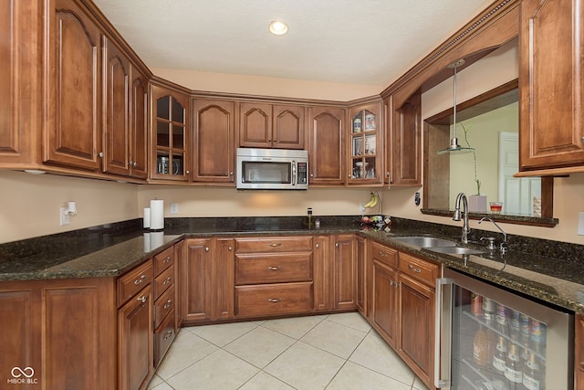 kitchen with beverage cooler, dark stone countertops, sink, hanging light fixtures, and light tile patterned floors