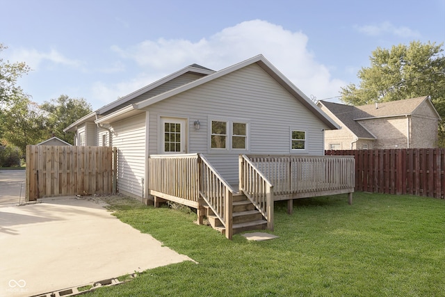 rear view of property featuring a deck, a lawn, and a patio