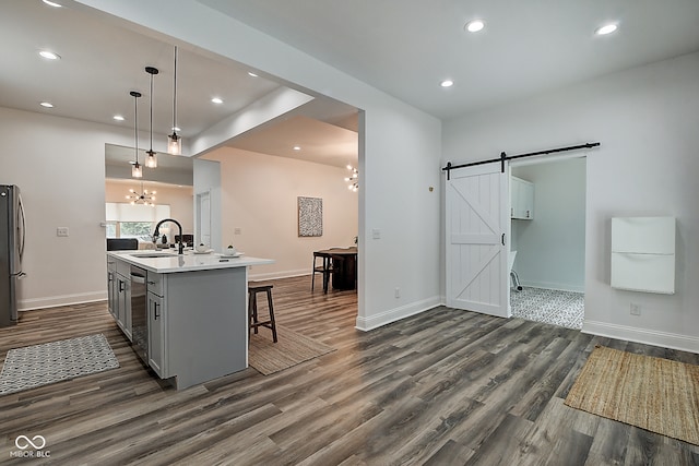 kitchen featuring pendant lighting, an island with sink, sink, an inviting chandelier, and a barn door