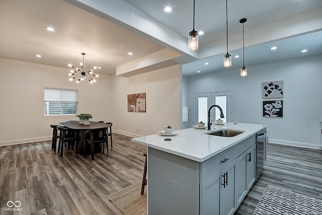 kitchen with an island with sink, dark wood-type flooring, decorative light fixtures, and sink