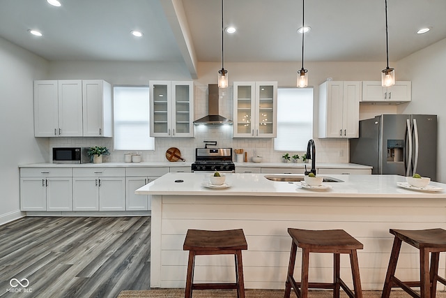 kitchen with appliances with stainless steel finishes, wall chimney exhaust hood, and white cabinetry