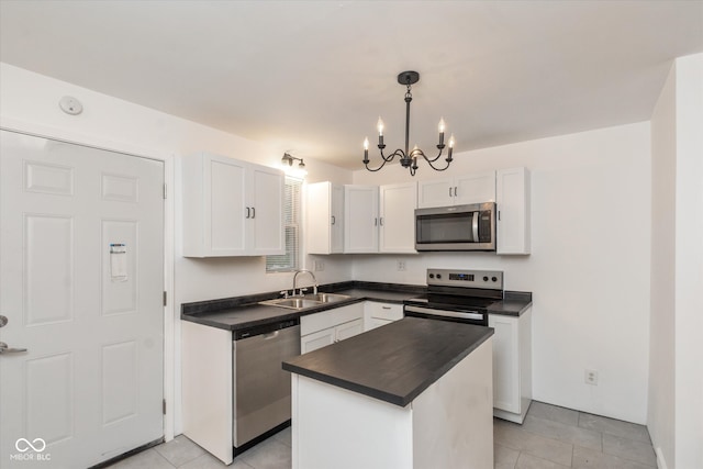 kitchen with appliances with stainless steel finishes, white cabinets, a center island, sink, and a chandelier