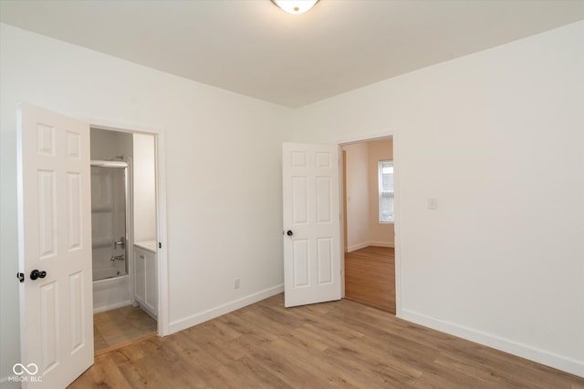 unfurnished bedroom featuring connected bathroom and light hardwood / wood-style flooring