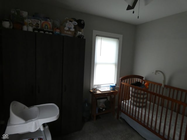 bedroom with ceiling fan, a crib, and carpet