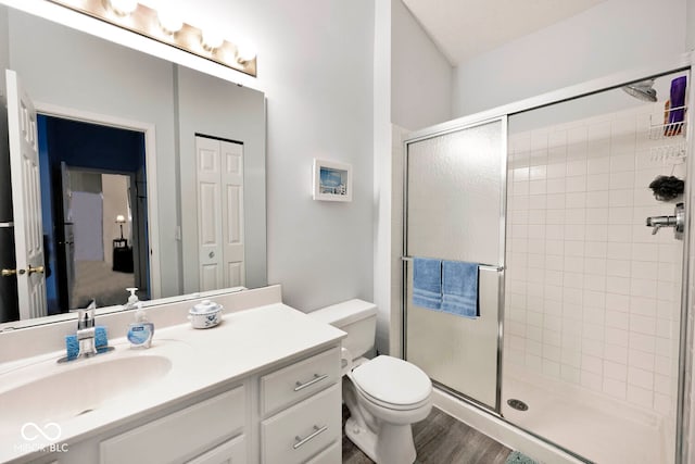 bathroom with walk in shower, hardwood / wood-style floors, vanity, and toilet