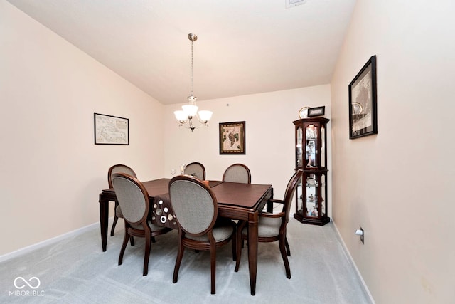 dining area featuring light colored carpet, a notable chandelier, and vaulted ceiling