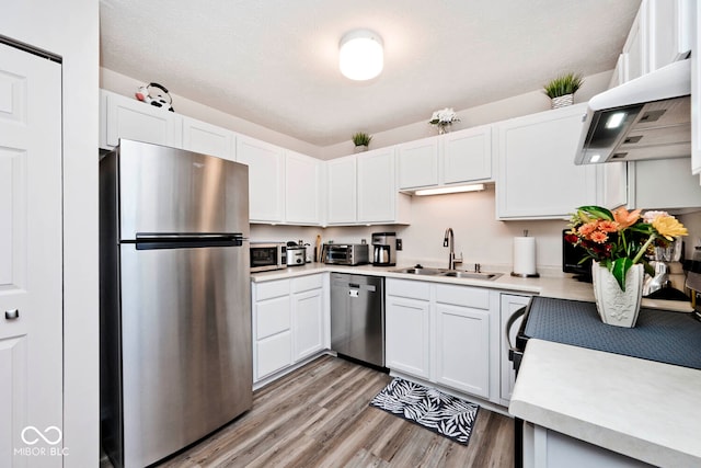 kitchen featuring white cabinetry, stainless steel appliances, a textured ceiling, light hardwood / wood-style flooring, and sink